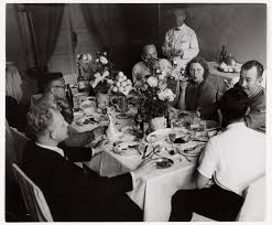 Setting out dishes and silverware, plating hors d'oeuvres, filling the water pitcher, trimming green beans, putting rolls in a basket, and ferrying sides to the table. John Steinbeck Hosting A Dinner Party Ussr International Center Of Photography