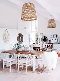 A boho dining room with a beautiful eastern rug, an arrangement of decorative plates, a wooden table and wicker chairs. Get The Look White Wood Coastal Boho Dining Room