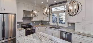 Traditional but unusually shaped kitchen with a white painted cabinets, seapearl quartzite countertops, tradewinds tint mosaic backsplash, paneled appliances, dark wood island with hidden outlets. 35 Fresh White Kitchen Cabinets Ideas To Brighten Your Space Luxury Home Remodeling Sebring Design Build