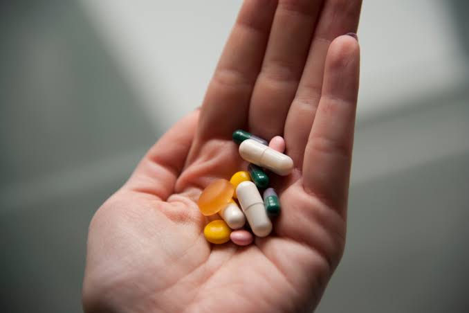 Assorted vitamin and supplement bottles mixed with medication, illustrating overlapping active ingredients