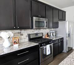 If you are considering white to reface your existing kitchen cabinets, or for new cabinetry altogether, you are not alone in your color choice. Dark Cabinets White And Gray Granite Countertops And Travertine Tile Bac Backsplash Kitchen Dark Cabinets Kitchen Remodel Small Backsplash With Dark Cabinets
