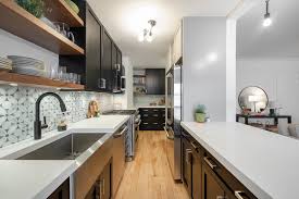 Here, a patterned floor and dark base cabinets ground the space, while the upper cabinets in a lighter color draw the eye up toward the ceiling. Learning To Love Your Small Galley Kitchen In Nyc