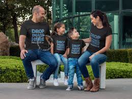 Placeit Parents With Kids Wearing Different Tees Mockup Sitting On A Bench While Outdoors Family Disney Shirts Matching Disney Shirts For Family Disney Family Vacation Shirts