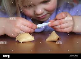 young girl reading fortune cookie message Stock Photo