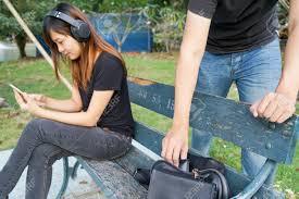 How to steal a phone. Thief Trying To Steal The Wallet In The Bag While Woman Using Mobile Phone And Listening To Music On Sofa In The Park Stock Photo Picture And Royalty Free Image Image 71470910