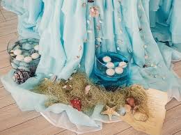 A beach wedding table with a net table runner, dried herbs, air plants, buoys and bottles and metallic goblets. Diy Beach Wedding Decoration Creative Ideas For A Stylish Decor
