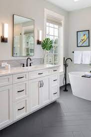 Bathroom interior with marble walls, a double sink standing on white countertops and a two vertical mirrors hanging above it. Black And White Bathroom White Bathroom Cabinets Master Bathroom Renovation White Master Bathroom