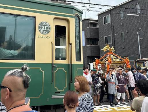 江の島天王祭 海上渡御を終えたお神輿が、江の島弁天橋を渡り、龍口寺の前で腰越・小動神社のお神輿と合流しました。 2基のお神輿が並ぶ姿も美しいけれど、ここでのもう一つの主役が江ノ電。お神輿のすぐそばを徐行しながらスレスレで抜けていくさまが、また気持ちを ...