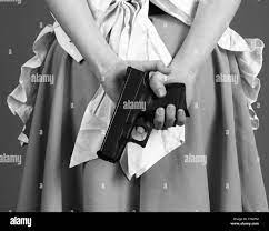 Young woman in an anomie dress with a gun behind her Stock Photo - Alamy