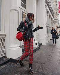 Picture Of A Black Sweater Red Plaid Pants Black Boots A Black Leather Jacket A Gey Scarf And A Red Backpack For A Comfy Look
