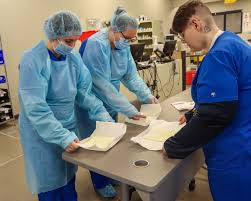 TCAT Dickson Pharmacy Technology instructor Kristy Garmon explains the  process of handwashing and applying Personal Protective Equipment (PPE)  before completing a sterile compounding assignment to students Caden Link  and Ashley Sellars. Pharmacy