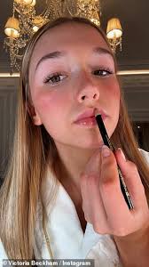 Harper Beckham, 13, is glued to her phone as she steps out in Paris holding  £1,850 Goyard tote bag while stylish mother Victoria tries to keep low-key 