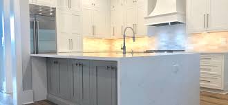 A stainless steel range and oven is flanked by classic white cabinets with nickel hardware. White Kitchen With Waterfall Island