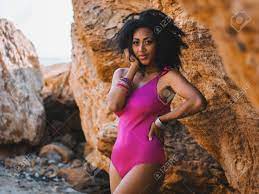 Portrait Of Cheerful Black People, Pretty Happy Young African American  Woman Smiling. Rocks Beach. Sexy Girl In Pink Swimsuit And Jewelry Enjoying  Nature. Travel, Holiday Concept. Stock Photo, Picture And Royalty Free