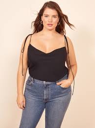 4k00.11tired plus size beautiful african woman in pajama sitting on cozy bed, stretching and massaging neck and shoulder muscles after hard day while relaxing and preparing for good night sleep in bedroom. 12 Of The Best Plus Size And Size Inclusive Brands Teen Vogue