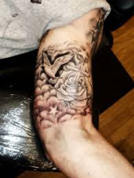 The cloud tattoo surrounded by flowers and skulls as well. Tattoos Design Tattoo Picture Pictures And Meanings Bicep Tattoo Bicep Tattoo Men Inner Bicep Tattoo
