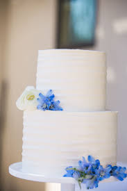 Simple White Wedding Cake With White And Blue Flowers Cake By Ruth And Ranshaw Photo By Meghan Ro White Wedding Cake Wedding Reception Flowers Wedding Cakes