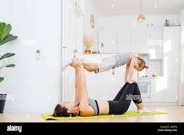 Young mom and her son doing yoga together, she supports him in a plank  suspended in the air. In a spacious kitchen Stock Photo - Alamy