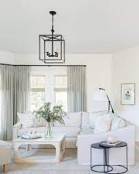 Whitewashed Wood Coffee Table Nestled Around A Light Gray Sectional And Round Iron Nesting End Tables Under An Iron Interior Design Interior Modern Living Room