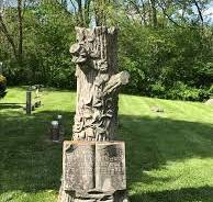 A gravestone in the shape of a tree. The dates on it are ...