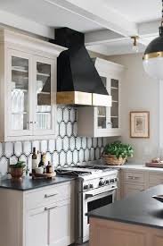 Beautiful Taupe Kitchen Features A Black And Gold Range Hood Fixed Between Glass Front Light Taupe Cabinets Taupe Kitchen New Kitchen Cabinets Kitchen Remodel