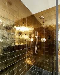Black And Gold Floor Tiles A Brushed Gold Shower Head Is Mounted To Shiny Gold Grid Shower Wall Tiles Over Black Grid Floor Tiles Gold Tiles Bathroom Shower Wall Gold Shower