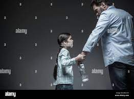 Forbidden topic. Very young girl with two long braids wearing jeans skirt  and striped shirt catching hand of her daddy while watching him, isolated  on Stock Photo - Alamy