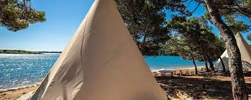 Eine gruppe sitzt zwischen autos an ihren zelten und isst zusammen. Auf Geht S Zum Glamping Alle Campingplatze Jetcamp Com