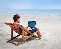 person working on a laptop on a beach resmi