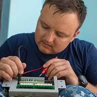 Electronics Technician 3rd Class Chris Elmendorf tests the connectivity of  a circuit board in the micro/miniature repair room.