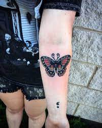 Dark Butterfly Tattoo With Bold Outlines Decorated With Red Yellow And White Near A Black Semicolon Tattoo Butterfly Tattoos For Women Tattoos Rose Tattoos