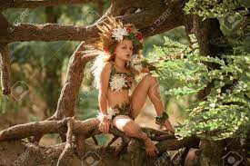Beautiful Little Girl In Image Of Nymph Dryad With Floral Head Wreath Sits  On Tree Roots In Magical Fairytale Forest . Stock Photo, Picture and  Royalty Free Image. Image 84048911.