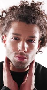 sexy fashion guy with curly hair rubbing palms, holding hands