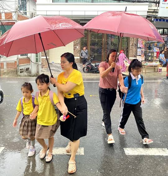 Thầy cô che ô cho học sinh trong mưa