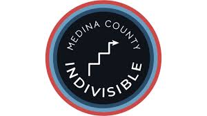 A circular logo with the text "MEDINA COUNTY INDIVISIBLE" in white, featuring a zigzag line design in the center. The background is black, surrounded by red and blue rings.