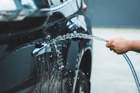 Lavar el auto con agua debajo de las mangueras afuera Rutinas del hogar  Cuidar el vehículo Primer plano | Foto Premium