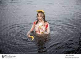 Eine wunderschöne nackte Muse im Wasser mit etwas bunter Körperfarbe auf  ihren sexy Kurven. Topless Mädchen mit Bananen. Mehr Beschreibung ist nicht  nötig für dieses sinnliche und erotische Bild. - ein lizenzfreies