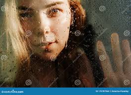 Kaplin De Agua Sobre El Vidrio En Foco. Detrás Del Cristal Una Silueta  Borrosa De Una Niña. La Niña Está Mirando Al Marco. Foto de archivo