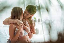 selective focus of shirtless man kissing girlfriend with big breast in  bedroom 