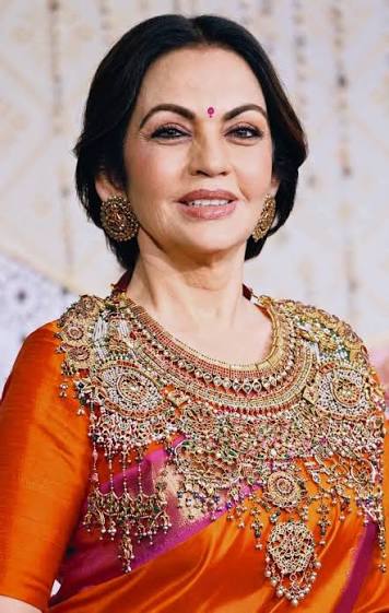 InPics | Nita Ambani stole the spotlight at the Ganpati celebrations with her stunning festive look. Dressed in a vibrant orange-magenta saree, she completed her traditional ensemble with an exquisite studded necklace