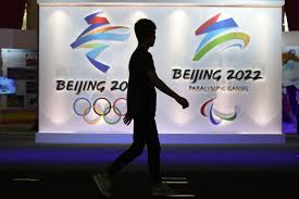 A chinese man wears a protective mask as he walk in front the logos of the 2022 beijing winter olympics at national aquatics centre on april 9, 2021 in beijing, china. 2022 Beijing Olympics U S Backs Away From Boycott