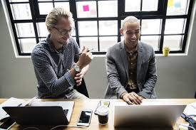 Two Men Sitting Beside Each Other In Front Of Laptops Business Strategy Employee Engagement Digital Marketing Agency