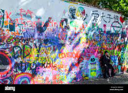 Prague, Czech Republic - June 27 2019: Asian couple during pre wedding  photoshoot in front of famous John Lennon Wall in Czech capital. Graffiti  wall inspired by famous artist. Popular tourist place