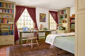 A guest bedroom with a home office space with bookcases and a wooden desj by the window for comfortable working. How To Combine A Home Office And Guest Bedroom This Old House