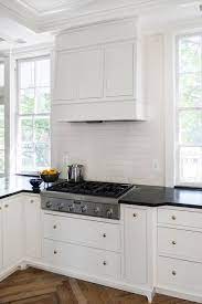 Try using gold hardware like this to tie the varied elements together. White Kitchen Cabinets With Brass Hardware And Black Countertops Transitional Kitchen