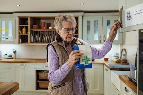 Someone reaching into a kitchen cabinet to store or retrieve a medicine bottle