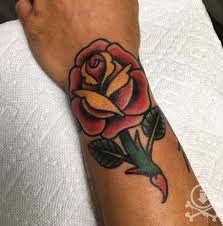The rose tattoo here is done in american traditional style, giving it a cartoonish look due to the thick black outlines, the thorn elements, and the extra line detailing. 12 Oz Studios Beautiful Traditional Style Rose Tattoo By Brendan