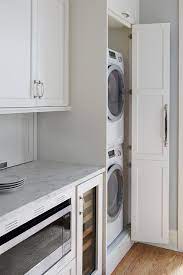The washers and dryers offer flexible installation possibilities, and only one electrical outlet is needed since the washer plugs into the dryer. Galley Style Kitchen With Hidden Stacked Washer And Dryer In Cabinet Transitional Kitchen