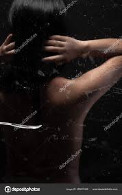 回头看性感裸女艺术裸露的黑发亚洲女人性感的姿势带着感情在浴室的淋浴玻璃蒸汽中激起浅浅的阴影和轮廓在黑暗的背景复制空间——