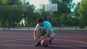 Black and green basketball court. Handsome Sporty Fit Black Basketball Player Tying Shoelaces On Outdoor Court Getting Ready To Play Streetball Game In Early Morning Healthy Lifestyle Guy Preparing For Sports Training Outdoors Stock Video Footage